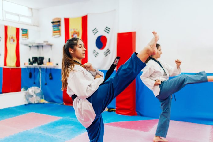 Two young women practice taekwondo in a training center