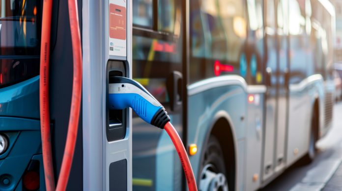 Stockphoto, copy space, modern public transport bus charging on an electric charging point, renewable energy theme. Clean green energy, zero waste.